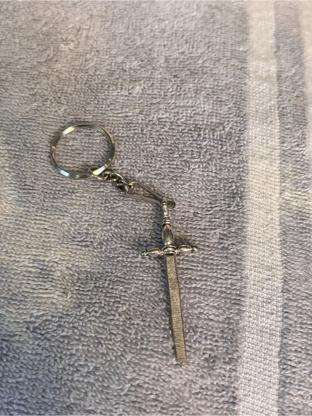 Medieval sword keychain features an intricate hilt and a textured blade pendant.